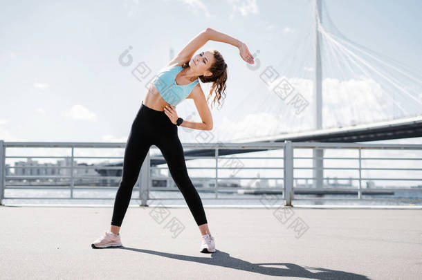 运动员过着健康的生活.有氧运动训练减肥。女人穿舒适的衣服。在城市里做运动。教练在训练前做热身运动.