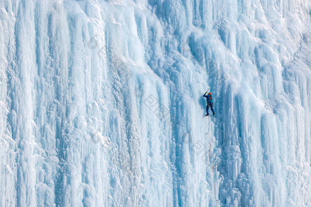 冰攀登者爬上垂直的墙.运动员们通过爬冰墙来享受户外的乐趣。积极参加体育活动的人.