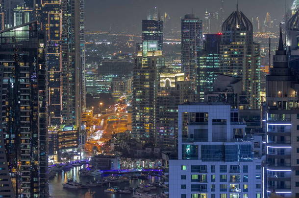 迪拜的滨海区和媒体城区有着现代化的摩天大楼和写字楼，夜间空中穿行。背景下的立交桥和市中心道路交叉口的交通情况