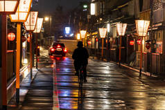 雨后独行骑自行车和出租车在穿过京都的灯笼里