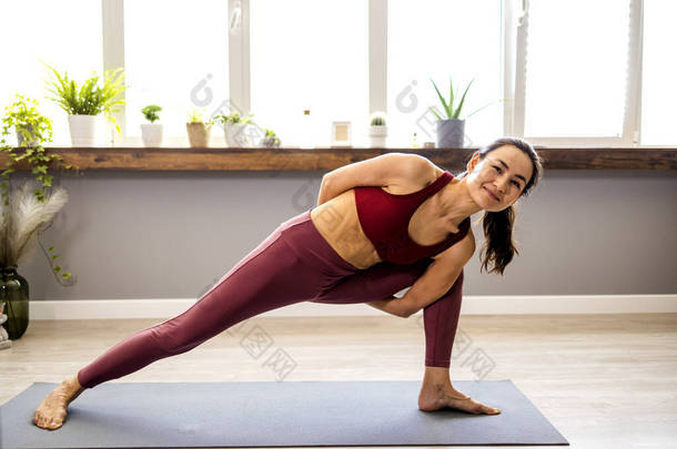 一位有魅力的亚洲女人练<strong>瑜伽</strong>，做伸展运动，做运动，穿运动<strong>服</strong>，穿上装，穿长裤，都是工作室的背景。<strong>瑜伽</strong>和训练的概念