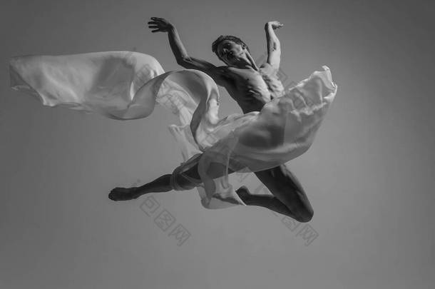 自由。优雅、肌肉丰满的男芭蕾<strong>舞蹈</strong>演员的黑白肖像，与面料、布隔离在灰色的<strong>工作室</strong>背景下。优雅、艺术、美的概念.