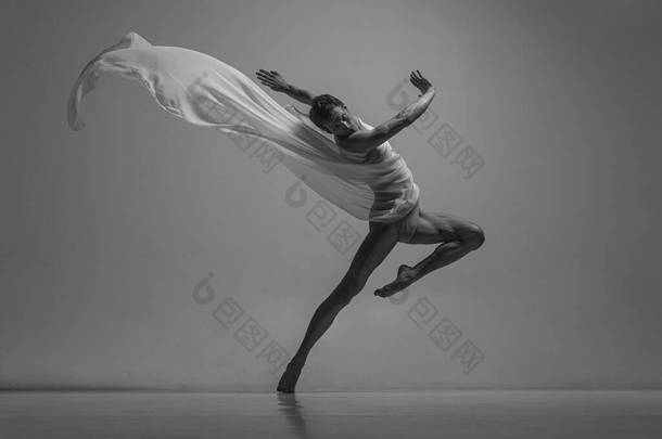 希望。优雅、肌肉丰满的男芭蕾<strong>舞蹈</strong>演员的黑白肖像，与面料、布隔离在灰色的<strong>工作室</strong>背景下。优雅，艺术，美的概念。无重量、灵活.