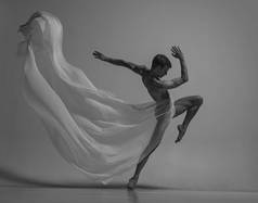 优雅、肌肉丰满的男芭蕾舞蹈演员的黑白肖像，与面料、布隔离在灰色的工作室背景下。优雅，艺术，美的概念。无重量、灵活.