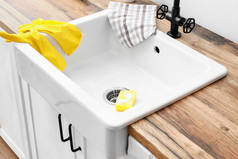 用橡胶手套、毛巾和海绵在木制柜台上洗碗的现代洗涤槽