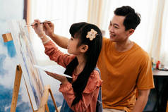年轻父亲的家人教他的女儿如何画画。父母身份和父亲身份.
