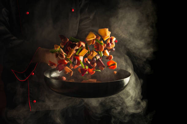 专业厨师在热锅里用黑色底火蒸煮食物.餐厅和酒店服务的概念。高级烹饪或大餐