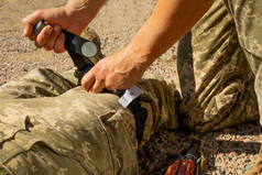 军医练习用止血带扎受伤士兵的腿。作战战术装备。战斗使用旋转栅门。军医的概念.