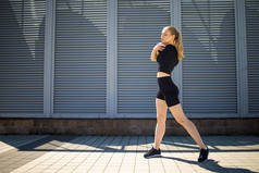健美短跑运动员身体特写，慢跑前做热身运动，伸展腿肌肉，女运动员准备腿做有氧运动，在城市进行户外运动.
