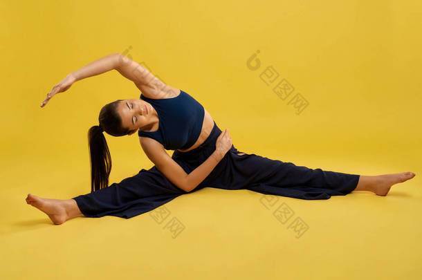 漂亮的女人<strong>练瑜伽</strong>，有伸展的腿，侧卧在室内。赤脚<strong>女孩</strong>，双目紧闭，试图在做<strong>瑜伽</strong>的时候手牵着脚，孤身一人。运动的概念.