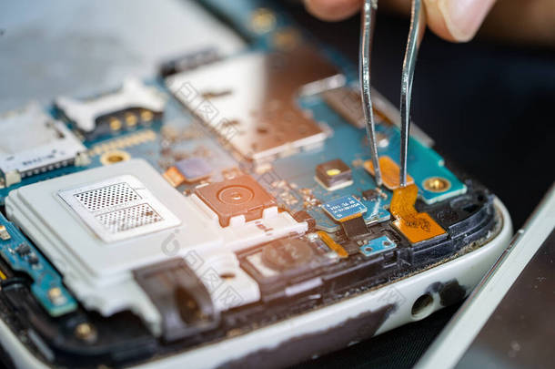 通过焊接铁来修理手机内部的技师.集成电路。数据,硬件,技术的概念.