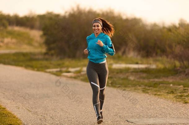 Young happy sportswoman running on the road in the morning. Copy space.