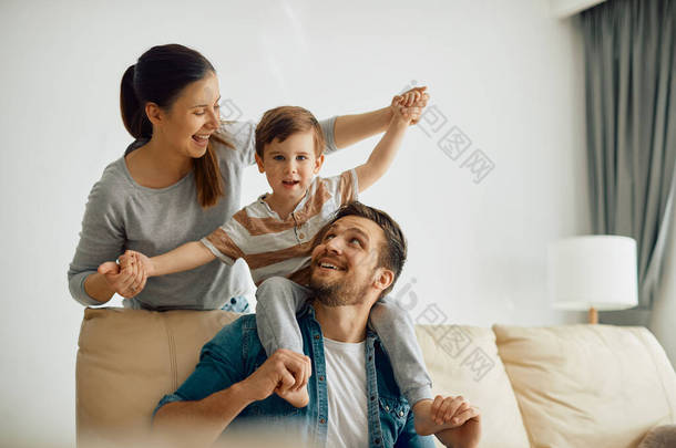 Happy parents having fun while playing with their small son at home.