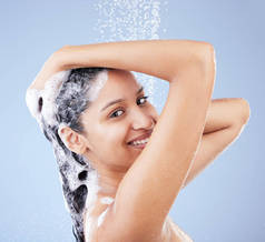 A wash was all I needed. a young woman washing her hair in the shower against a blue background