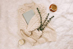 Knitted warm sweater, coffee, notepad and candle, flat lay. Winter lifestyle, top view