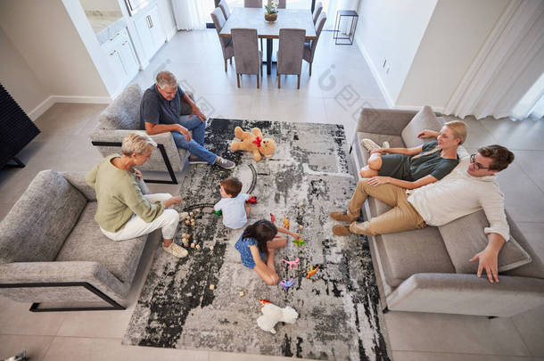 与父母、婴儿或儿童一起在客厅里的大家庭在地毯上玩耍，以促进成长、发展和健康。外祖母和外祖父在休息室与孩子们交谈，学习语言.