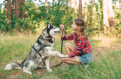 十几岁的女孩和她的西伯利亚哈士奇犬玩耍和玩乐。森林里带着狗的女孩