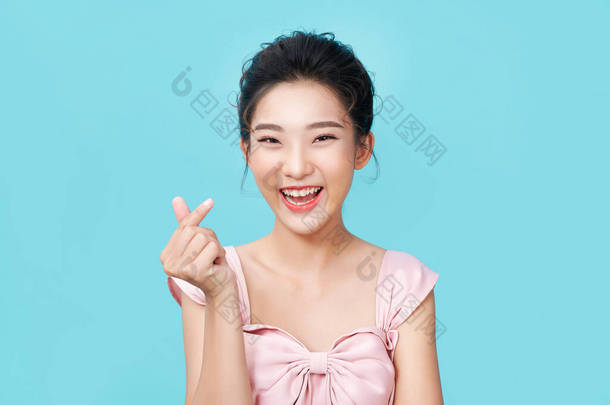 年轻、快乐、浪漫、有爱心的亚洲女人用手指塑造微型心形，表示爱情的迹象
