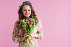 快乐的现代女人，有着长长的波浪般的黑发，郁金香花束，背景是粉红色的.