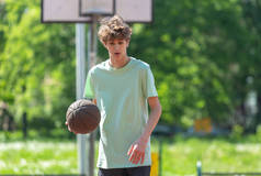穿着球衣的年轻可爱少年在球场上打篮球。体育、业余爱好、男孩的积极生活方式