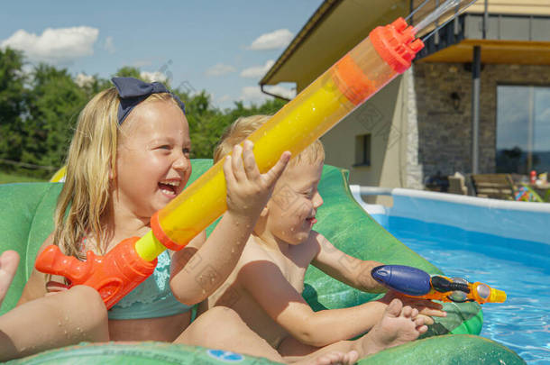 CLOSE UP: Happy and smiling children enjoying at water fight in the garden pool. Water games for hot