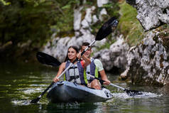 一对年轻夫妇在一条美丽的河流中享受着田园诗般的独木舟之旅，这条河流被茂密的绿叶环绕着.