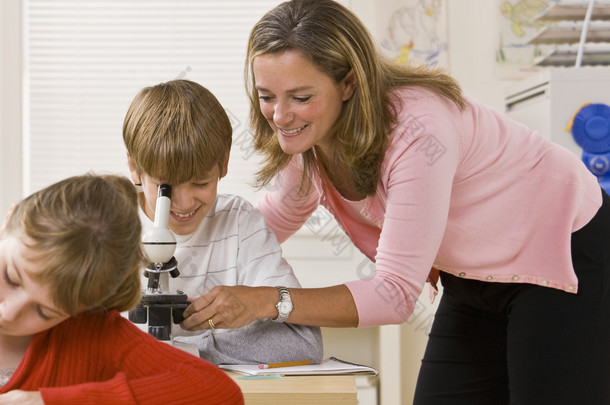 教师帮助学生用显微镜