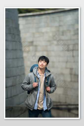 城市背包客在石头建筑中抬头看拉背包肩带