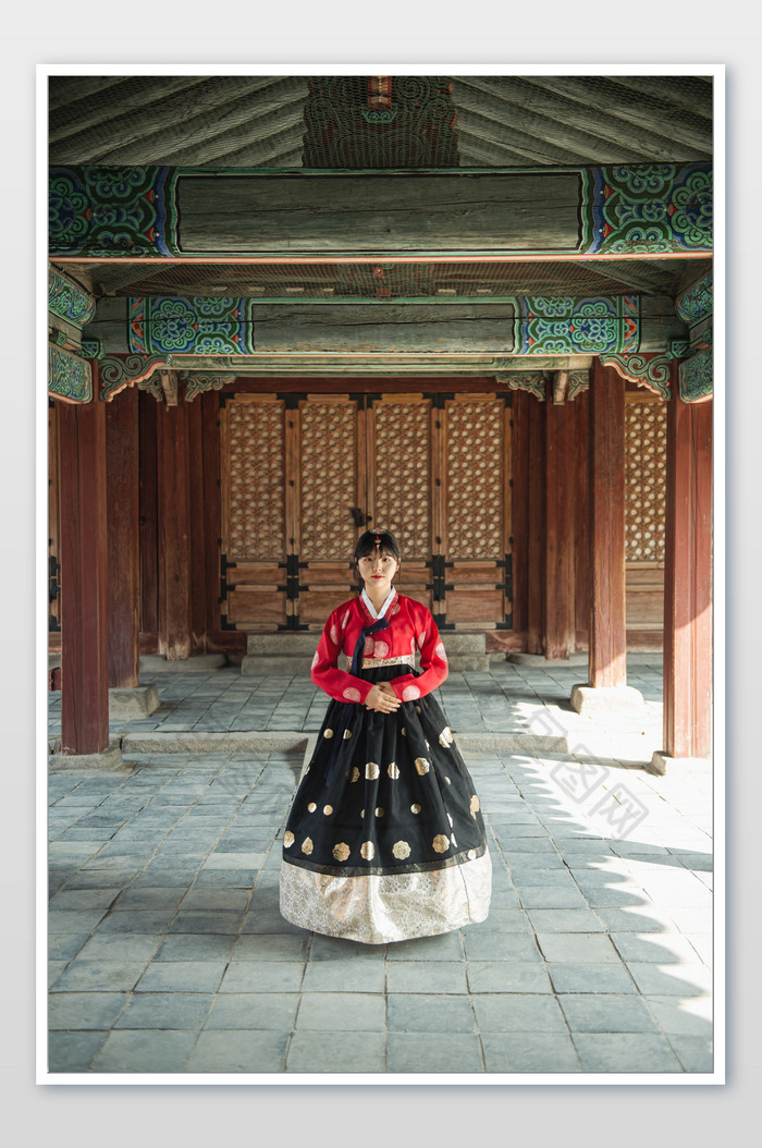 身穿红色韩服的少女站立在传统建筑下全景图片图片