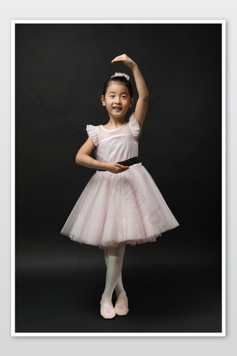 黑色背景穿着粉色纱裙摆芭蕾姿势的小女孩图片