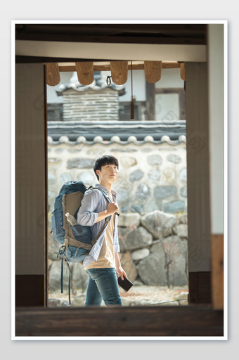 城市背包客驻足看石墙背景竖图