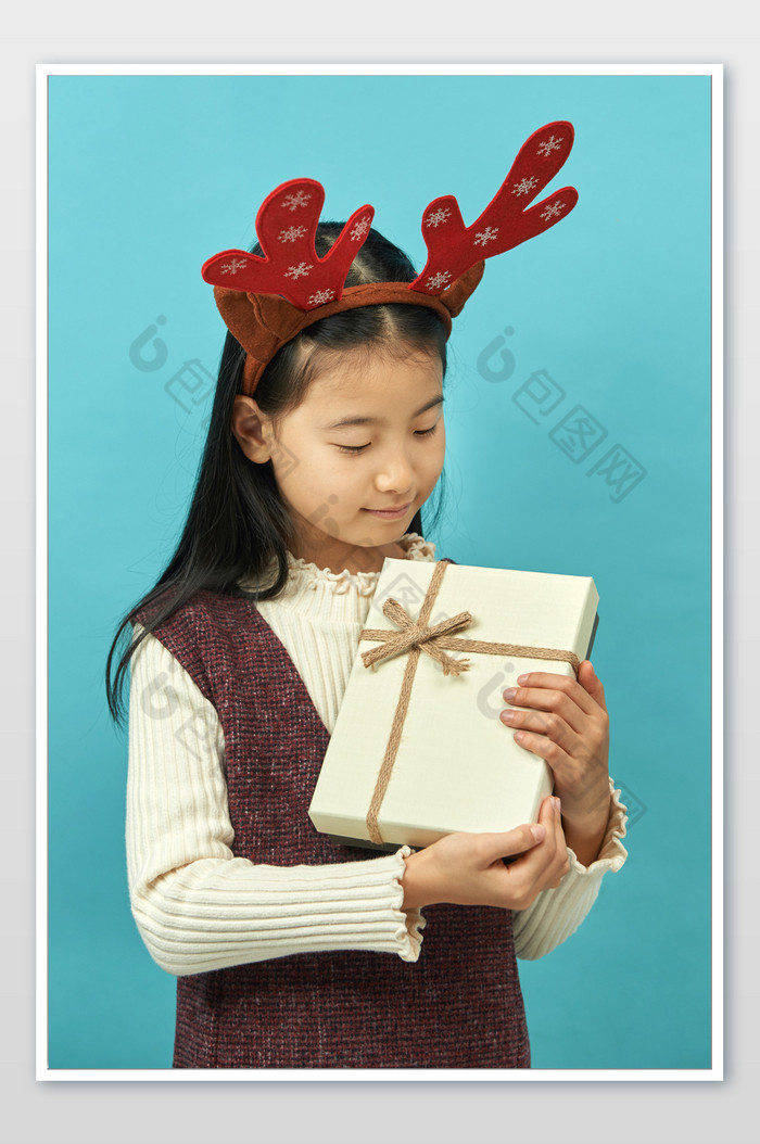 戴着圣诞鹿角的小女孩怀抱礼物图片图片