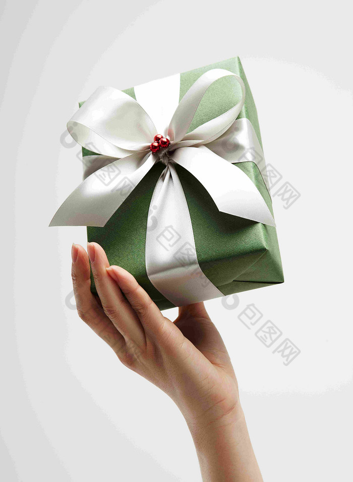 手持白色丝带绿色礼物包装盒静物摄影图