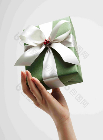 手持白色丝带绿色礼物包装盒静物摄影图