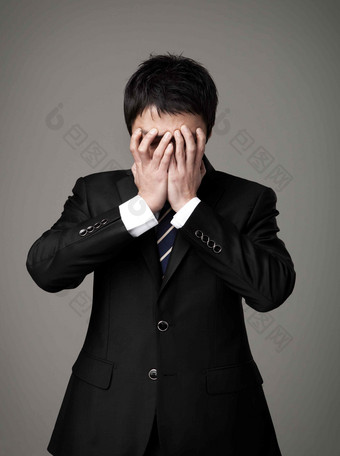 双手捂脸焦虑的商务男士场景摄影图