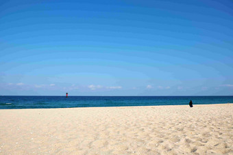 阳光沙滩湛蓝的海水与天空远处一瞭望塔