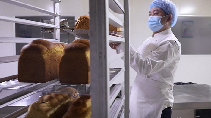 实拍面包工在操作间推作业车送面包