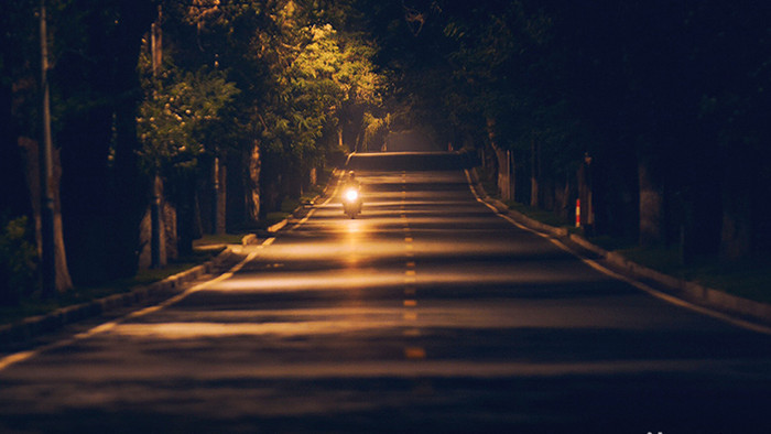 孤独感夜晚路灯下寂静马路上车辆行驶实拍