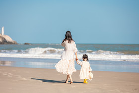 母亲牵着孩子在海边散步