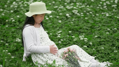人物形象孕妇坐在花丛中抚摸肚子实拍4K