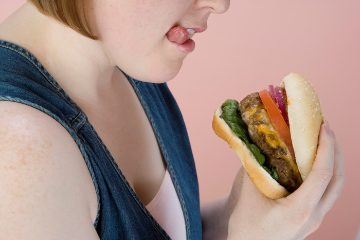 粉色调吃汉堡的女人摄影图