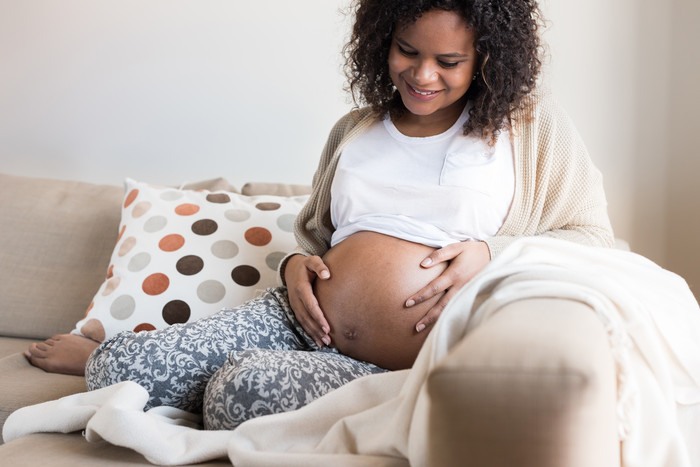 黑人孕妇坐在沙发上抚摸孕肚