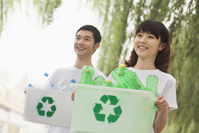 青年男女抱着装满塑料瓶的箱子