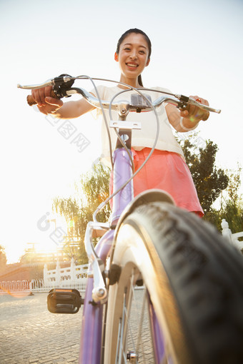 年轻的女人户外骑着自行车微笑出行摄影图片