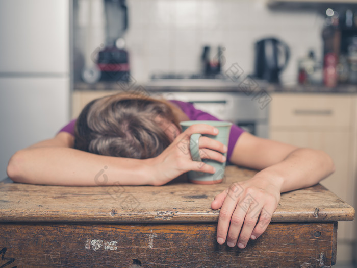 女人拿着杯子趴在桌子上