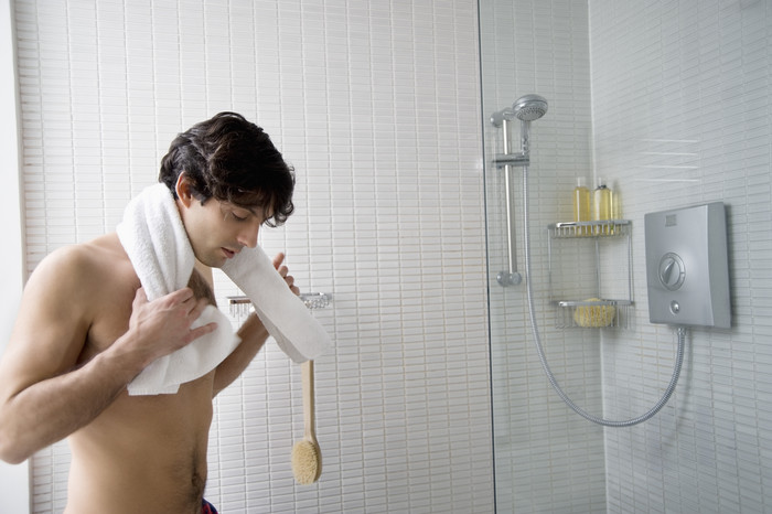 浴室里拿着白毛巾擦拭的男人