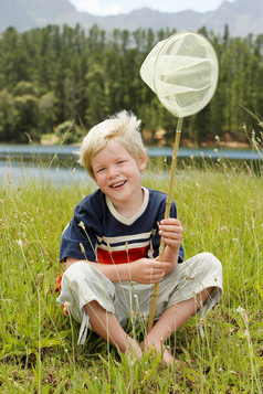 坐草地上拿渔网的小男孩