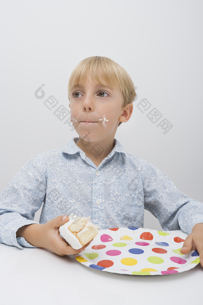 深色调吃蛋糕的男孩子摄影图