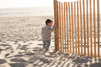 海滩上扶着栏杆的小男孩