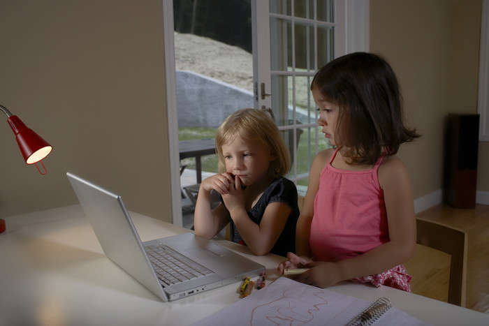 两个可爱的女孩台灯下看电脑